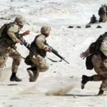 5 Soldiers Holding Rifle Running on White Sand during Daytime