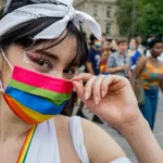 woman in white tank top with multi colored paint on face